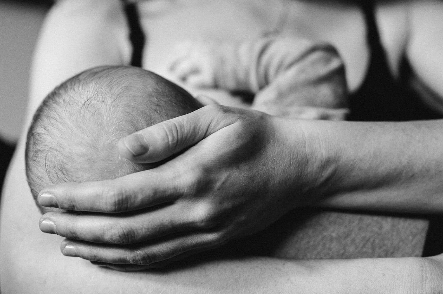 Schwarzweissfotografie eines Babys, das von seiner Mutter gestillt wird von Babyfotografin aus Zürich