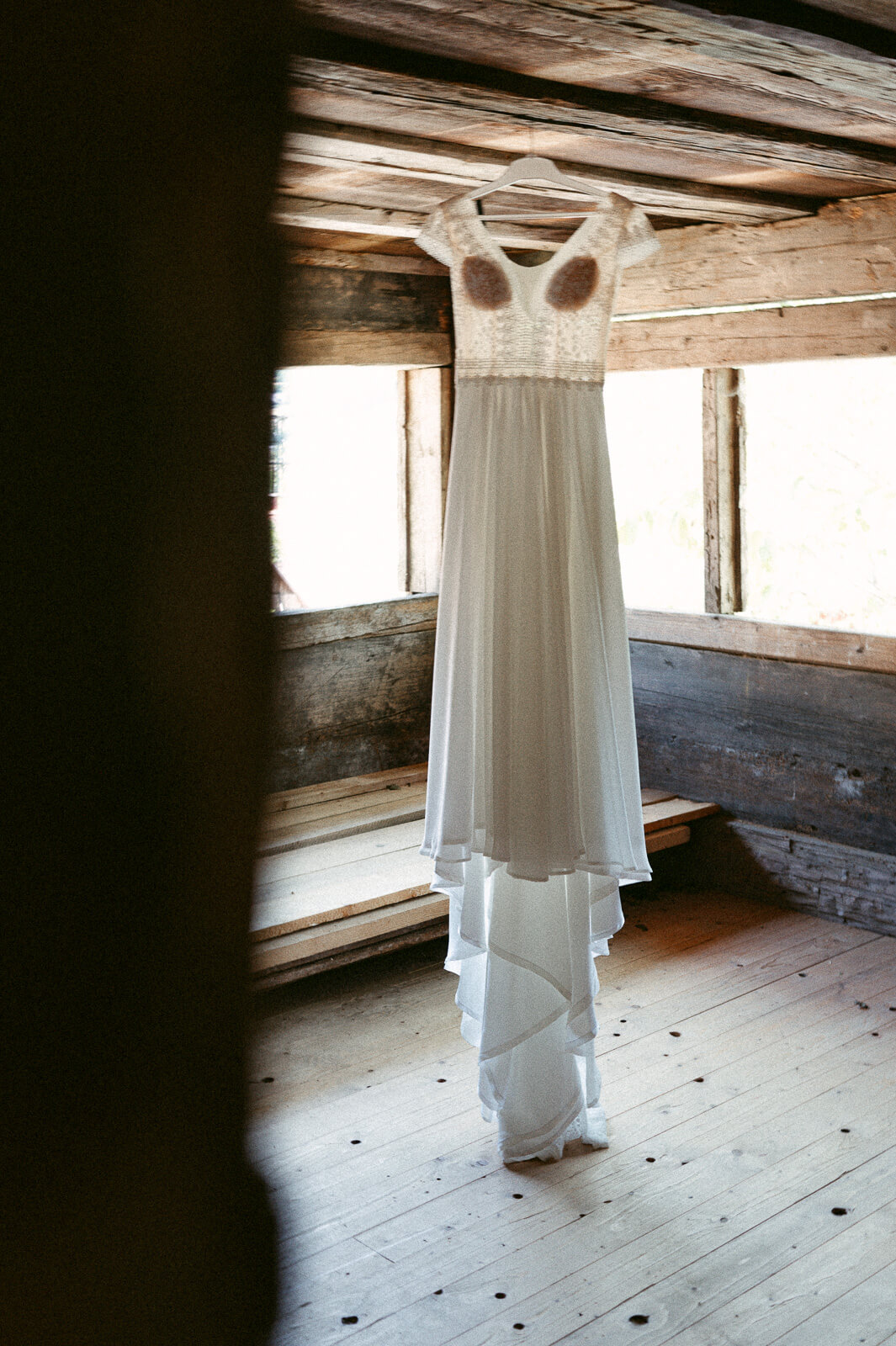 Hochzeitskleid hängt in einem Raum aus Holz von Hochzeitsofotografin aus Zürich